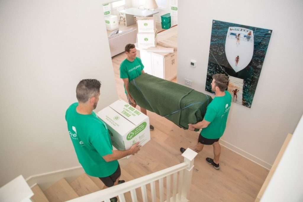 Three Movegreen team members carrying items down stairs